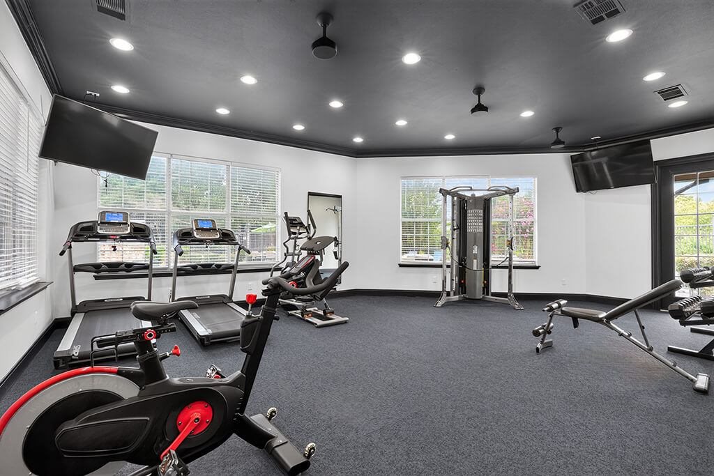 A spacious gym with a variety of exercise equipment including treadmills, stationary bikes, and weight machines.